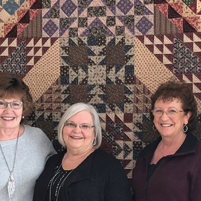 huron-perth quilters guild members in front of a quilt they made for a local hospice
