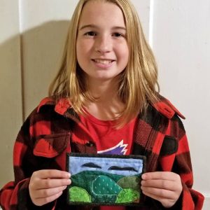 photo of young quilter assembling a quilted postcard at a sewing machine