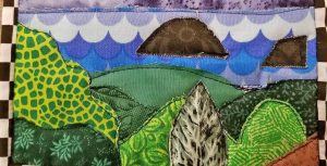 photo of fabric pieces machine quilted to resemble a landscape