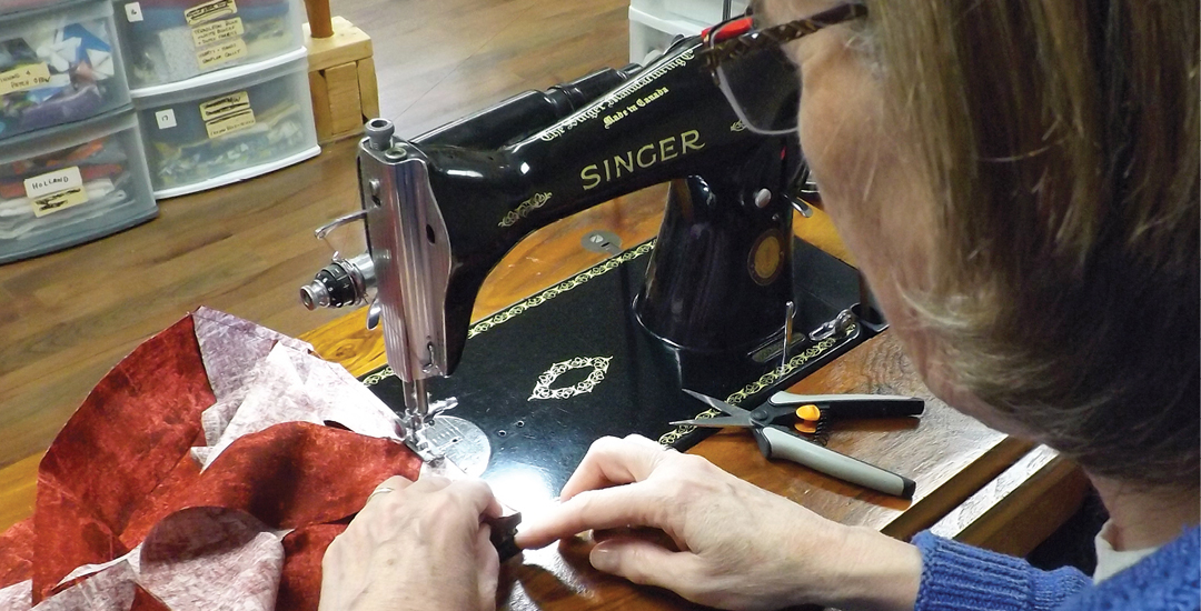photo of a woman sewing at a vintage sewing machine