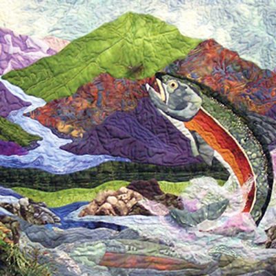 photo of an art quilt of a fish against a mountain landscape