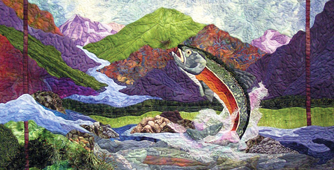photo of an art quilt of a fish against a mountain landscape