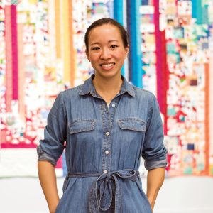 photo of andrea tsang jackson in front of a quilt