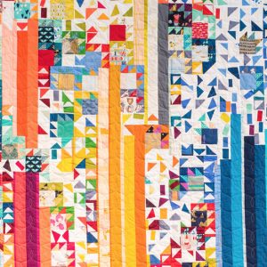 photo of a multi-coloured quilt with long strips and triangles